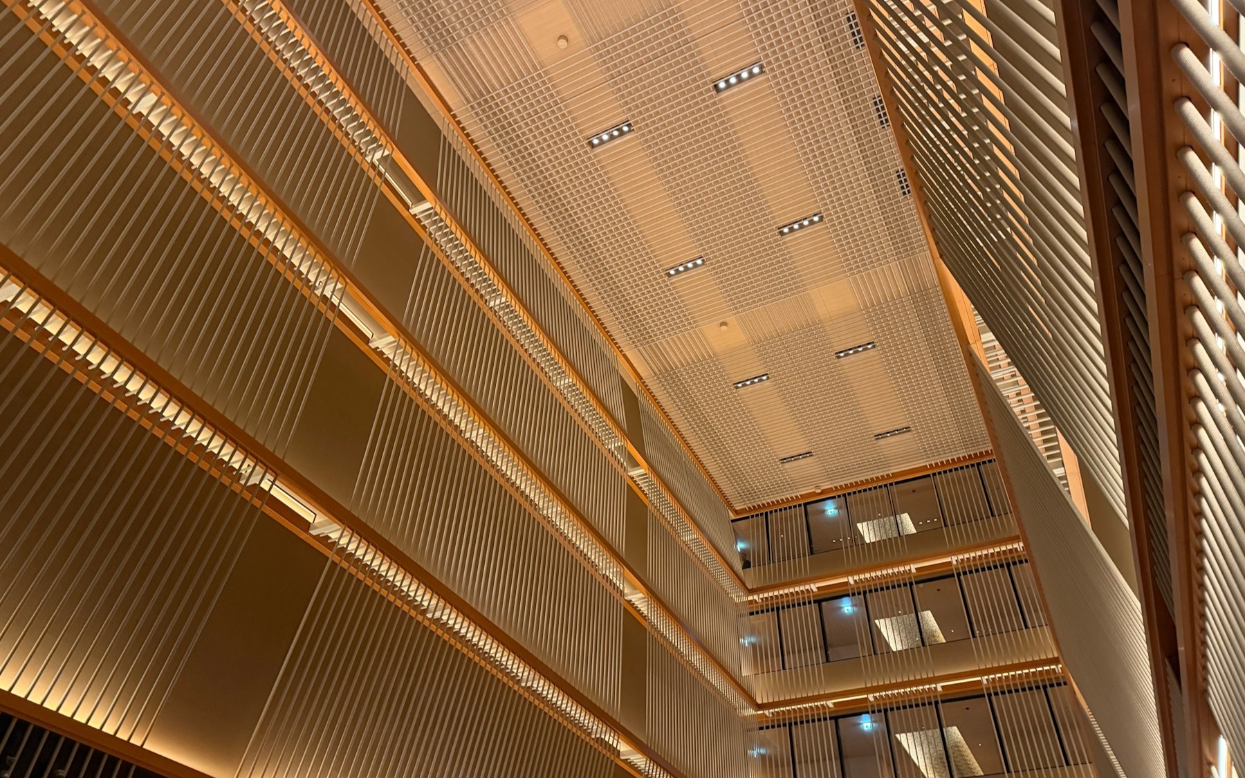 Warm architectural atrium with layered screens and light.